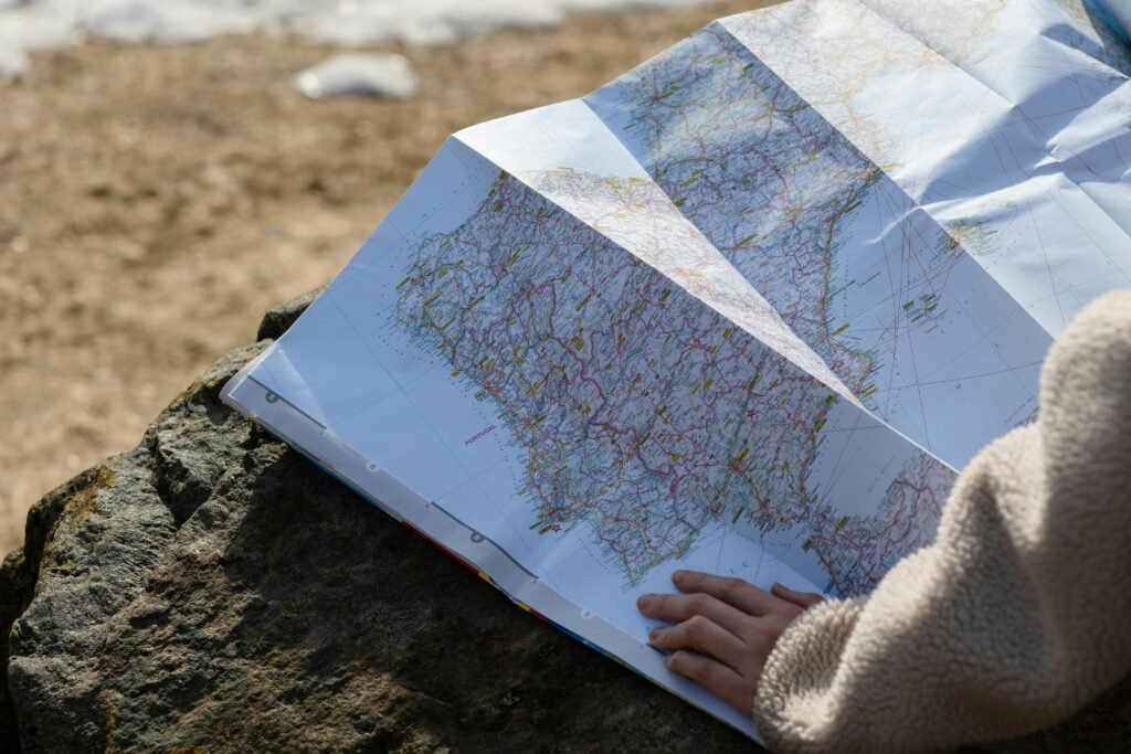 pexels-photo-7634707-7634707 A person studies a roadmap placed on a rock, embraced by natural sunlight outdoors.